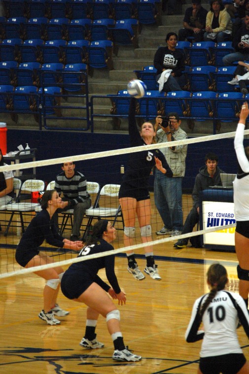 Ashley Vander Hey (#5) hits the ball over the net as Mer- edith Bard (#15) and Laura Colley prepare for the return.
