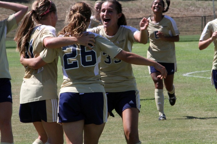 Kelly+Davis%2C+Megan+Anderson+and+Olivia+Collado+celebrate+freshman+Lauren+Hellers+game-winning+goal+against+Regis+College.%0A