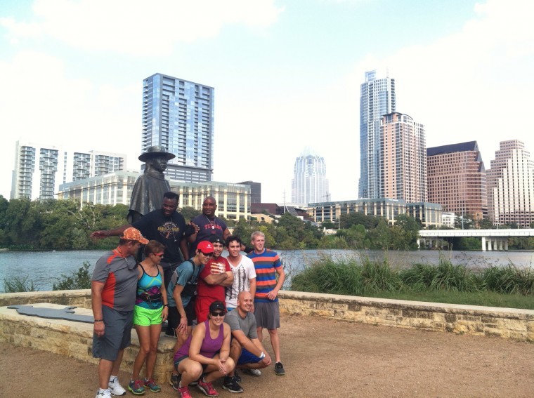 Participants on an Austin running tour pause for a photo with the iconic statue of Stevie Ray Vaughan on Lady Bird Lake.

