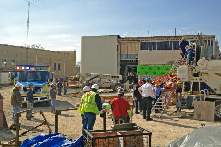 The fire department, EMS, and construction crew watch as emergency personnel prepare to slide a stretcher down at ladder after a worker was injured on the job Friday afternoon.
