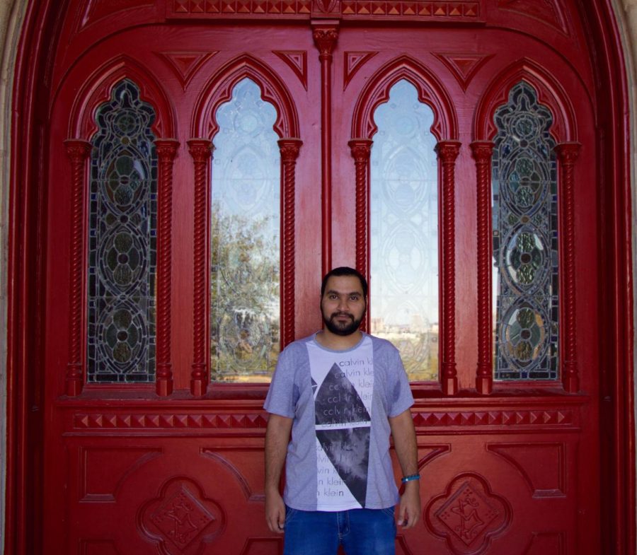 International student Omar Alazmi stands in front of the red doors.