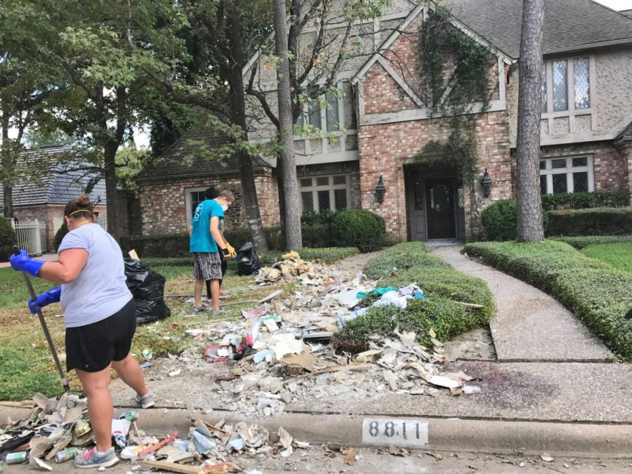 Campus Ministry volunteers rake and shovel debris onto the street from a water-damaged home in Spring, Texas, on Sept. 16.