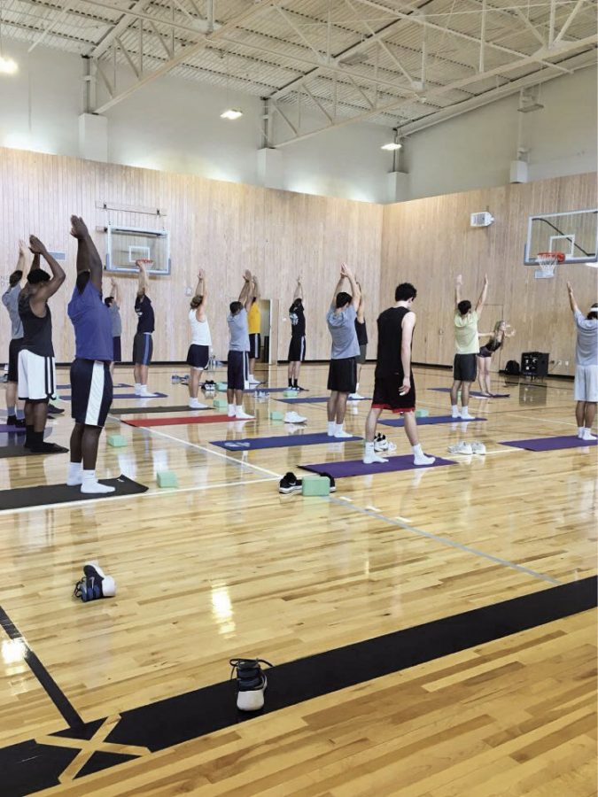 The men's basketball team is guided through a yoga flow, a series of poses that synthesize for a unified purpose in the body
