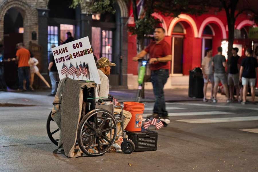 A homeless man is ignored by pedestrians on 6th street.