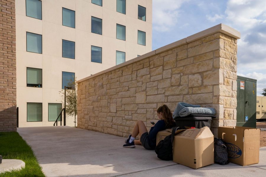 A student waits with her luggage outside the Pavilions residence hall. Students from three of the four wings will be unable to reside in the building for the remainder of the semester.