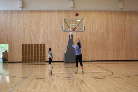 Club co-president Elyse Wick practices her free throw routine as fellow co-president Izzy Garza prepares to grab a rebound. 