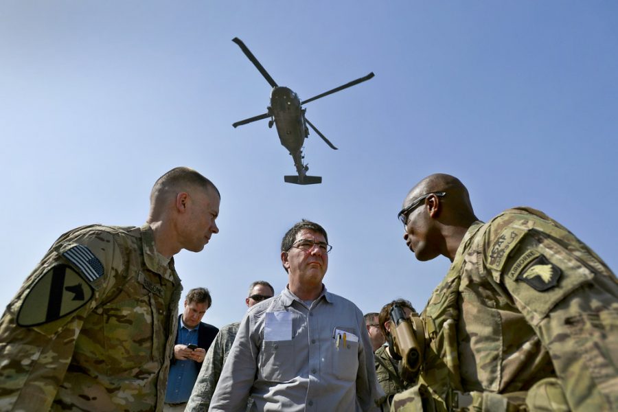 As a Black Hawk helicopter rumbles overhead, Deputy Secretary of Defense Ashton B. Carter speaks with Brig. Gen. Ron Lewis, right, during a visit to bases in Afghanistan, May 13.