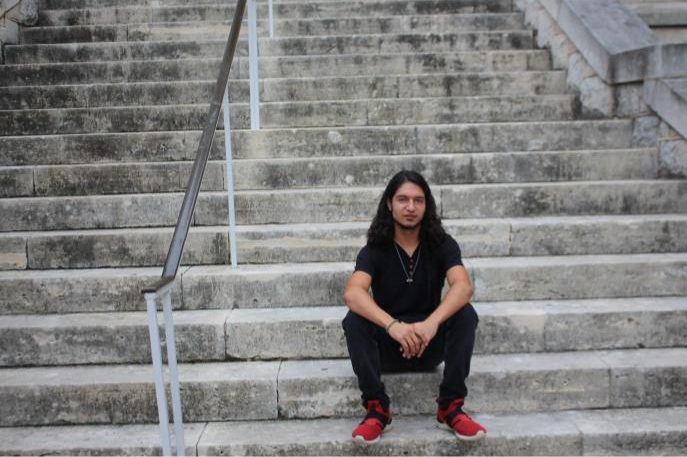 Santiago Clark sitting on the steps of Trustee Hall. Clark is a senior Entrepreneurship major at St. Edwards University. 