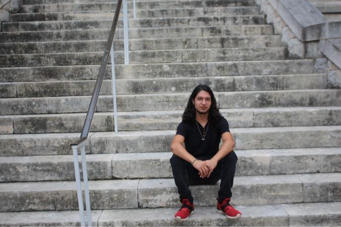 Santiago Clark sitting on the steps of Trustee Hall. Clark is a senior Entrepreneurship major at St. Edward's University. 