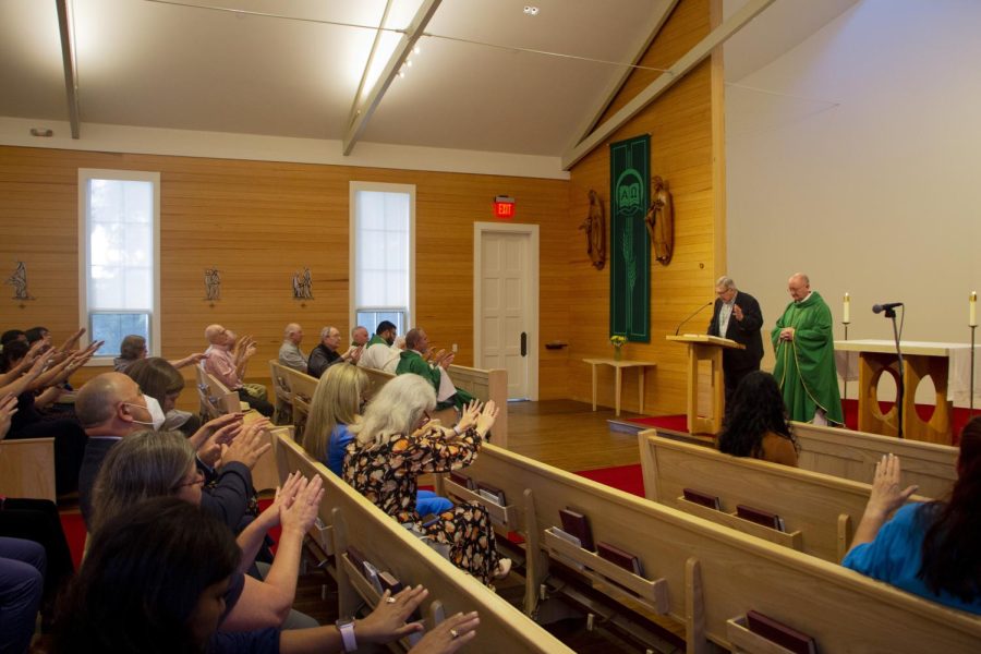 Members of the St. Edward's community extend their hands to bless Fr. Peter Walsh and wish him well.