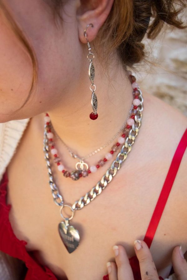 Mooney shows off a red necklace that was made by their aunt and a pair of earrings their friend made for them.