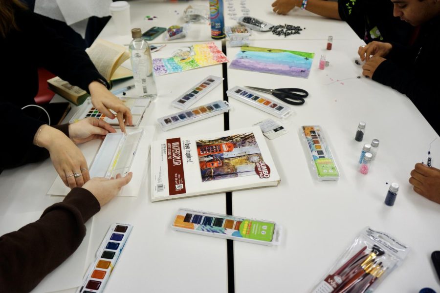 Students+gather+at+the+craft+table+to+partake+in+a+variety+of+artistic+outlets%2C+including+bracelet+making+and+painting.+