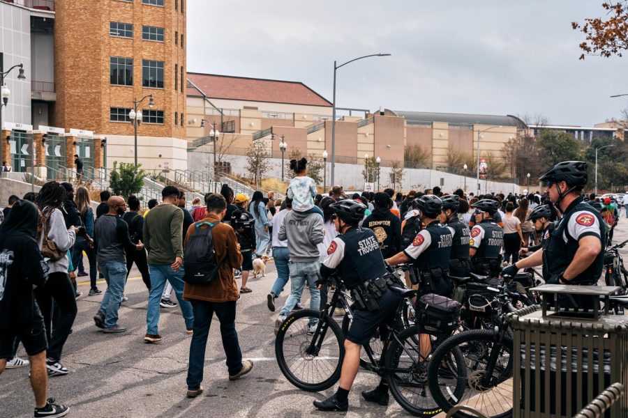 State troopers, mounted on their bicycles, observe the participants as they march on.