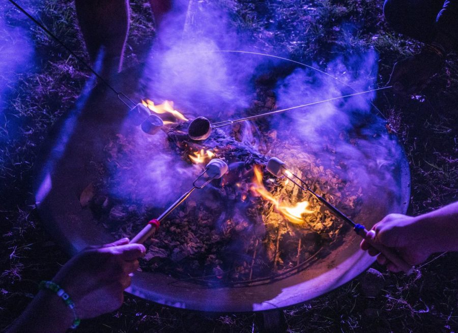 A group of students roast marshmallows around the fire during s’mores night held at the on-campus garden, created by Students for Sustainability. 