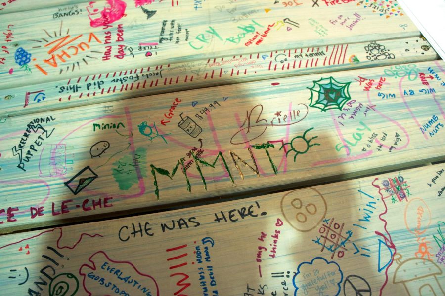 A picnic table beloging to the theatre department that sits decorated with the signatures and doodles of past and present students and performers. 