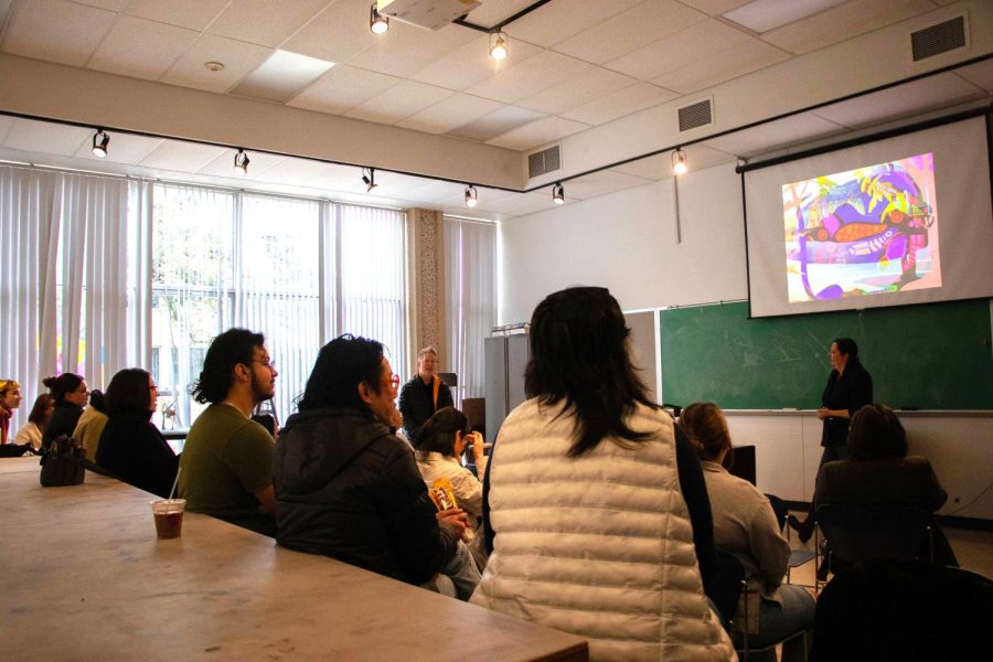 Students and faculty members listen to painter Wendy Deschene and environmental ceramic artist Jeff Schmuki. The artists discuss their work as individual artists and as the collaborative team to  create a biotech corporation called PlantBot Genetics. 