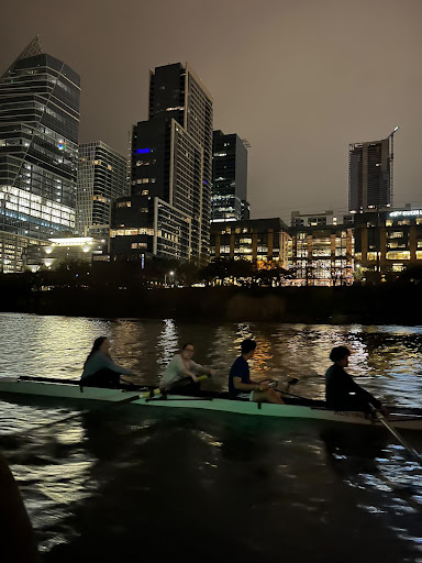 Sophomore Jana Ivey, sophomore Evelyn Schneider, senior Ibrahim Villalobos and freshman Omar A. Carmona Rdgz. practicing at dawn on Lady Bird Lake, in front of the rising city.