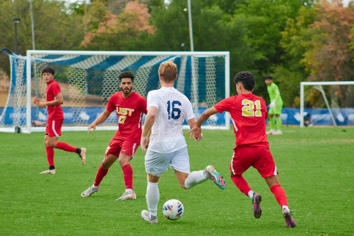 Graduate+midfielder+Todd+Fuller+faces+two+St.+Thomas+defenders.