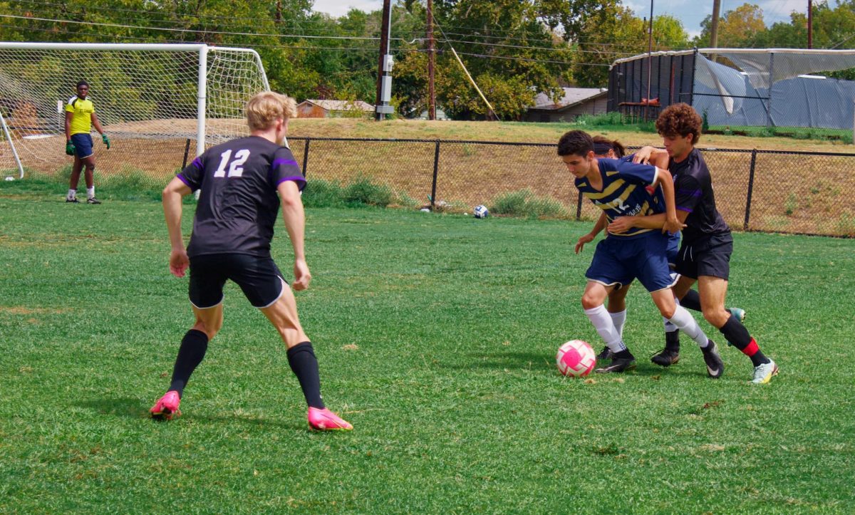 A member of the St. Edward’s men’s club team faces off against several members of the TCU team while trying to possess the ball.