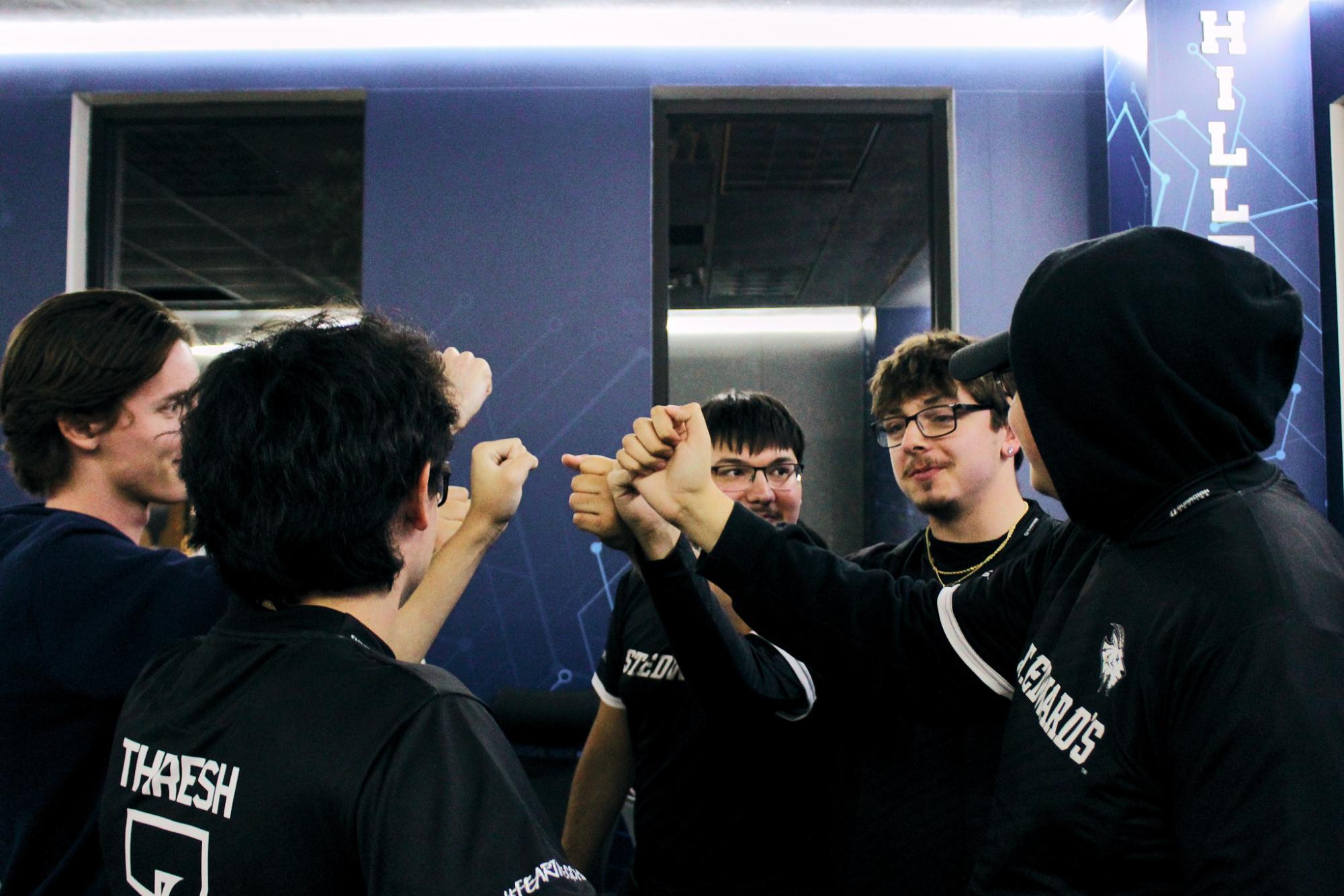 The Esports Call of Duty teams huddles together with their fists in the center, showing support for one another.