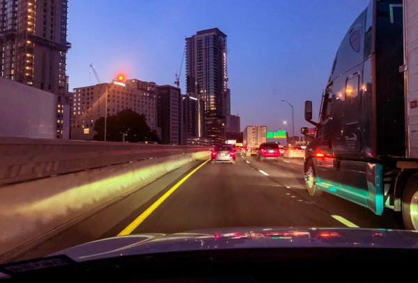 I-35 runs parallel to Downtown Austin, displaying a row of gleaming lights at dusk while drivers simultaneously sit in bumper-to-bumper traffic across three lanes.