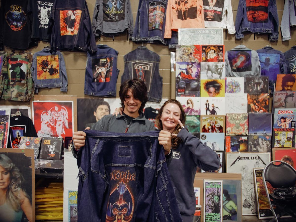 Born Late Records displays a custom Motörhead denim jacket in front of their booth. The company buys, sells and trades vinyl, CDs, tapes, shirts and other memorabilia. Their storefront is located at 2920 Race Street, Fort Worth, TX, and their Instagram is @bornlaterecords.