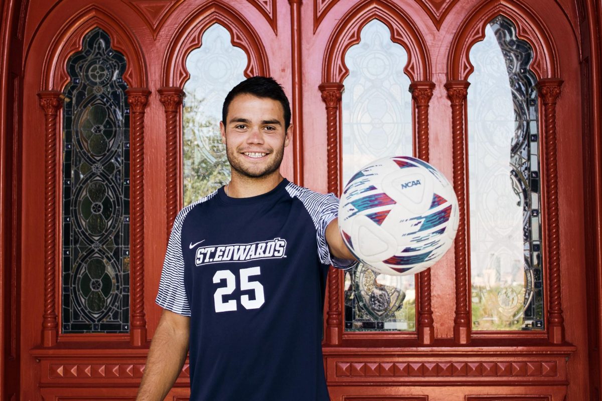 Jason Lyons, 22-year-old center-back for the mens soccer team, stands in front of Main Buildings iconic red doors. Lyons initially walked through these doors as a freshman recruit for the soccer team, but had to walk out of them while the soccer team was sunsetted. Now he will be finishing this legacy with his soccer team in tow. 