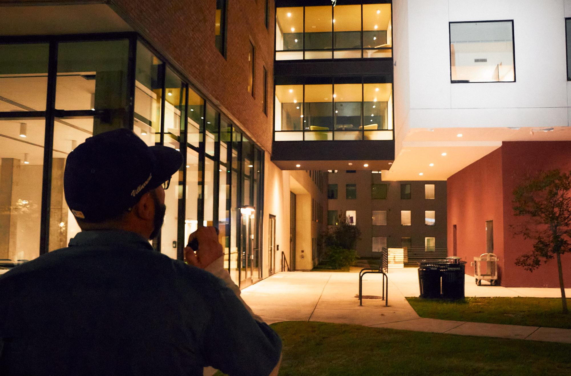 Erik Villanel with University Operations shines his flashlight at dead bulbs under the St. Andre apartments. This complex was one of the main stops on the walk.