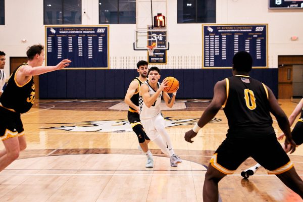 Hilltopper Gavino Ramos rushes toward the hoop from the top of the key, juking one St. Francis player. Two more defenders enter from the sides to try and stop the St. Edwards from scoring.