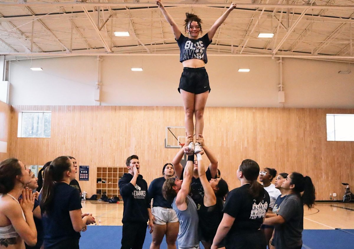 At practice, new coach Austin Wilder has the team try various cheer techniques such as stunts. 
