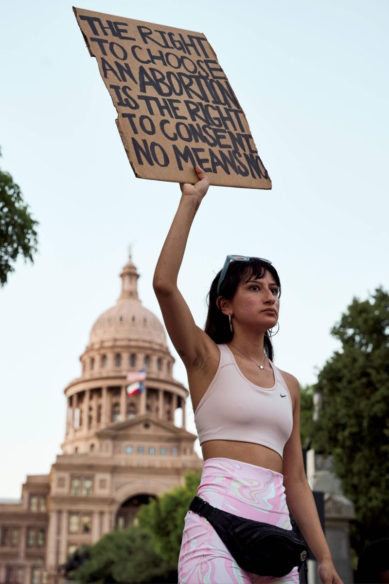A protester takes a stand with a sign in hand that relays a message on the importance of consent.