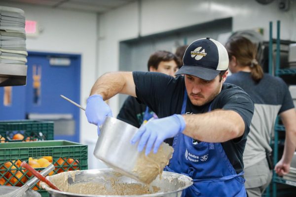 Senior Brian Romaniello is transferring batter to cooking trays, later cooking it to serve at dinner time. Students that are assigned kitchen duty in the morning usually cook lunch for the staff and the students to eat at noon. The other students who are assigned kitchen duty in the afternoon cook large amounts of food for Andre Houses biggest service provided: dinner. The average number of meals served during the week is around 500. Dinner preparations start in the early afternoon with students working with the volunteer chefs to make different foods each week. Whatever leftovers there are after serving the guests, students pack it up, drive to the CORE house and eat dinner together.