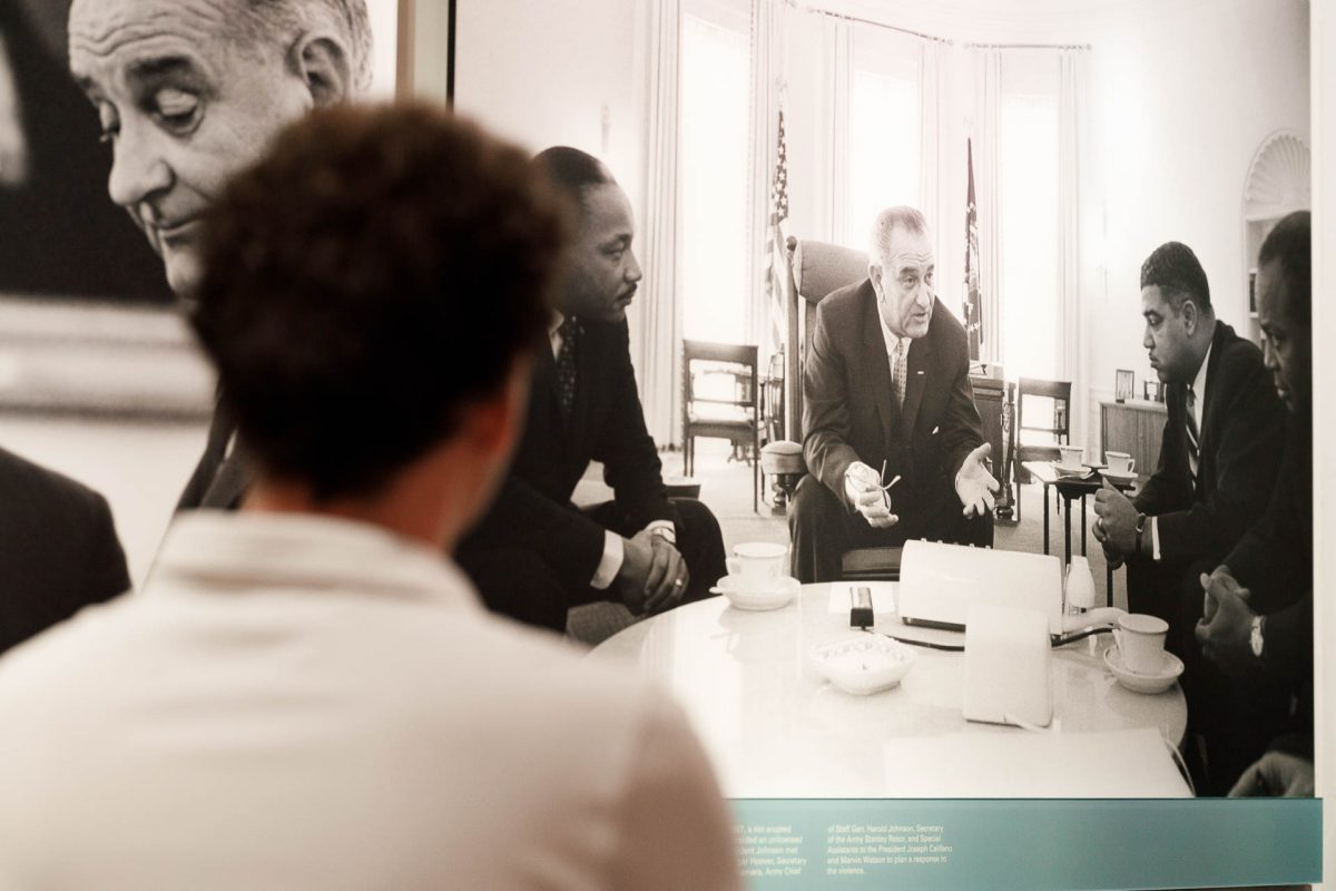 An+observer+admires+a+photograph+of+Johnson+in+discussion+with+prominent+Civil+Rights+Leaders+at+the+local+LBJ+Presidential+Library.