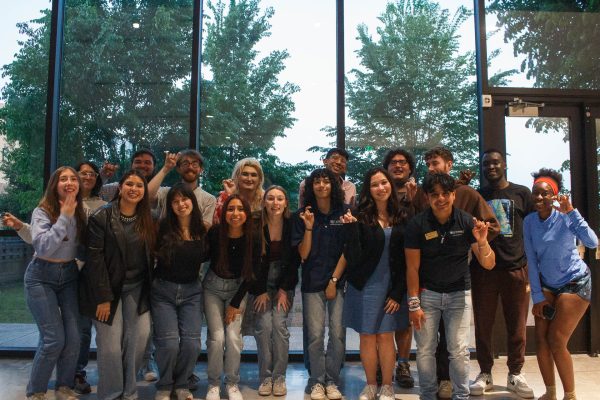 Members of Student Government Association, both current and incoming, pose with toppers up in the St. André Multipurpose Room during last week's senate meeting.