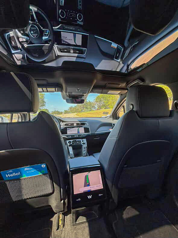 Inside a Waymo vehicle, passengers can observe the sleek, driverless setup. The dual screens display the current route, while also showing all surrounding vehicles and objects in real time.