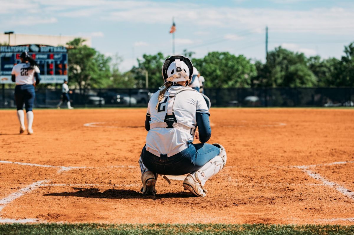 Senior catcher Sloane Hill sets up behind the plate during a St. Edward’s game this season. As her final collegiate season winds down, Hill said she will miss the everyday moments with her teammates — from bus rides to shared memories like the team once getting stuck in a crowded elevator during a road trip.