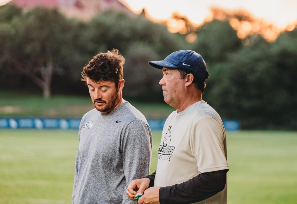 Current head coach Brian Young and associate head coach Corey Miller stand on the sidelines of Lewis-Chen Family field for the spring season.